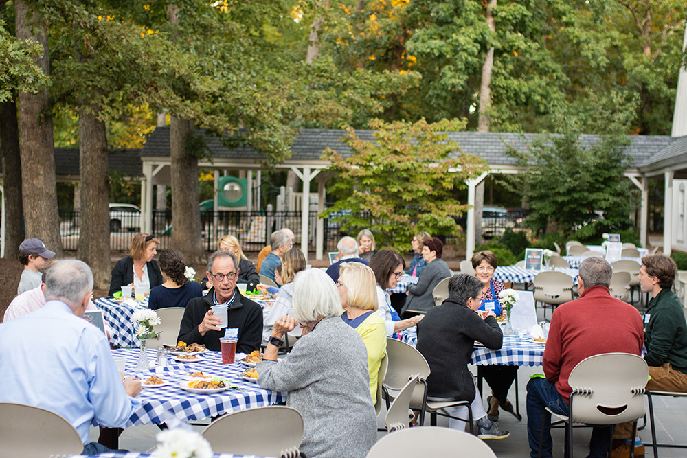 People eating around tables outside during Parish Supper